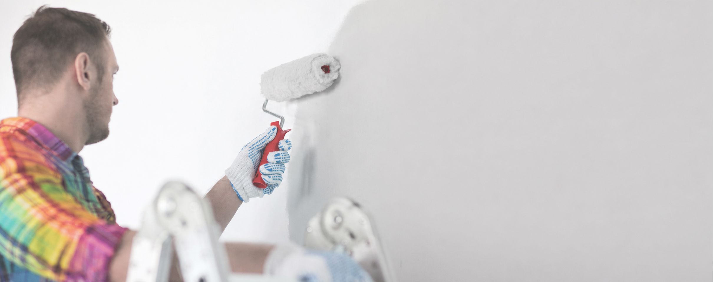 Maler bei professionellen Innenanstrichen mit Farbroller und weißer Wandfarbe