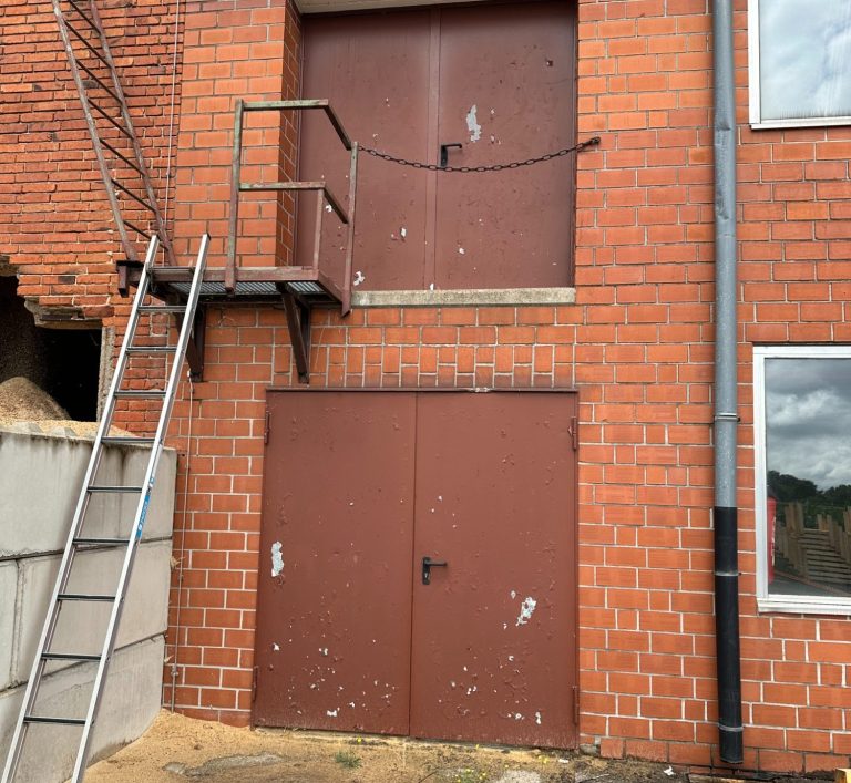Restaurierung zweier Industrietore an einer Ziegelsteinfassade.