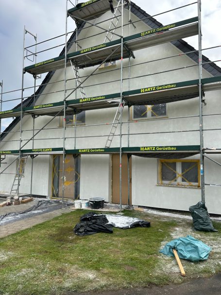 Fassade eines Hauses mit Baugerüst und unvollendeten Außenarbeiten.