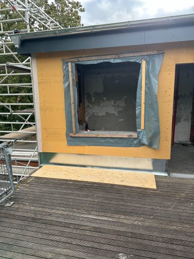 Offene Fensterlaibung mit Holzverkleidung an einem renovierten Gebäude.