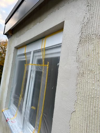 Fenster mit Plastikfolie und gelben Markierungen an der Gebäudeaußenwand.