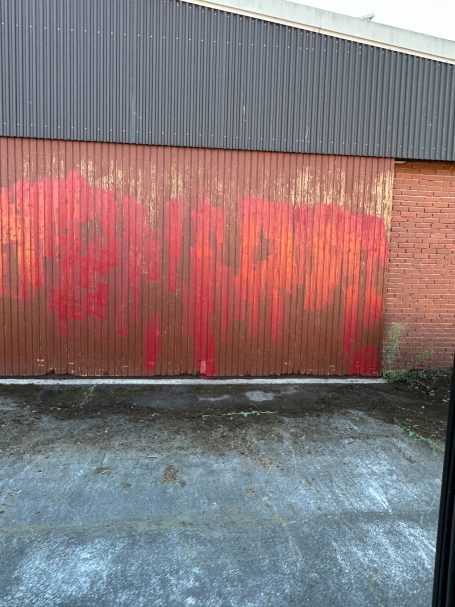 Altes Holztor mit roten und orangefarbenen Farbverläufen und Tropfspuren.