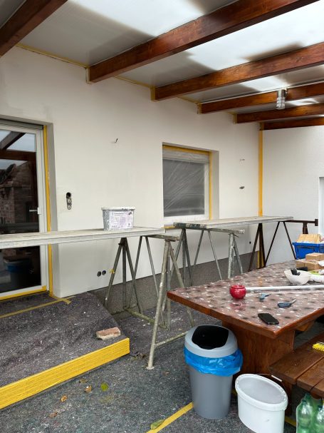 Renovierungsarbeiten in einem Raum mit Arbeitstisch und Baustellenmaterial.