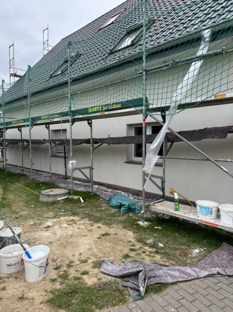 Baugerüst an einem Gebäude mit Materialien und Werkzeugen für Renovierungsarbeiten.