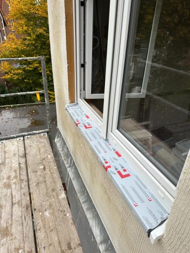 Fensterbank mit Baufolie auf einem Balkon, neben einem offenen Fenster.